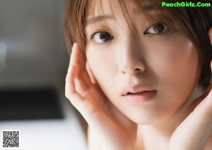 A close up of a woman with her hands on her face.