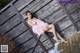 A woman in a pink dress sitting on a wooden fence.