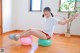 A woman sitting on an exercise ball in a room.