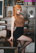 A woman in a brown top and black skirt posing for a picture.