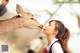 A woman is feeding a deer a piece of food.