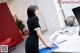 A woman in a black dress is standing at a desk.