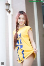 A woman in a yellow shirt is posing for a picture.