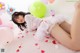 A woman laying on the floor surrounded by balloons.